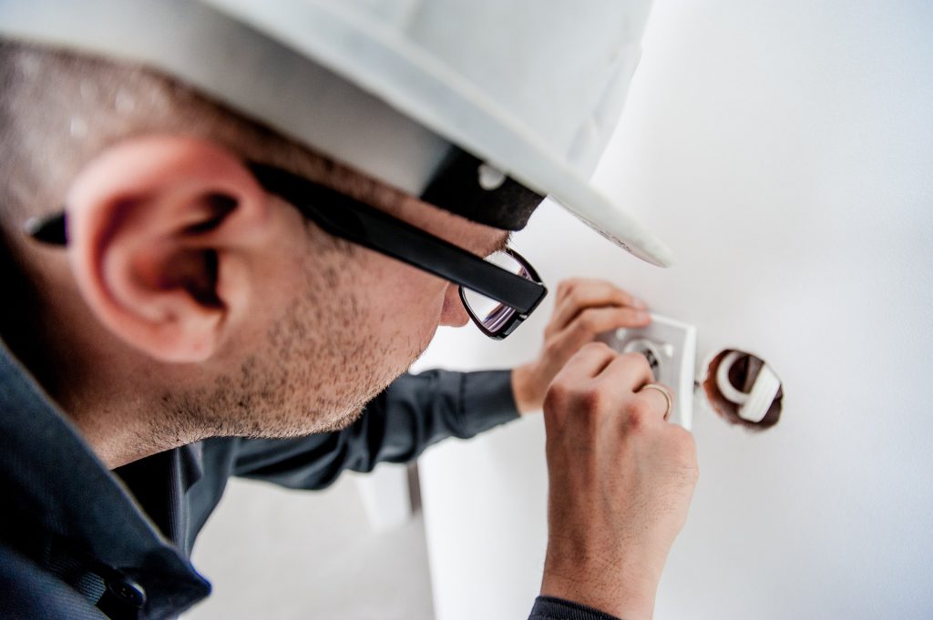 un electricien avec un casque qui travaille sur une prise de courant