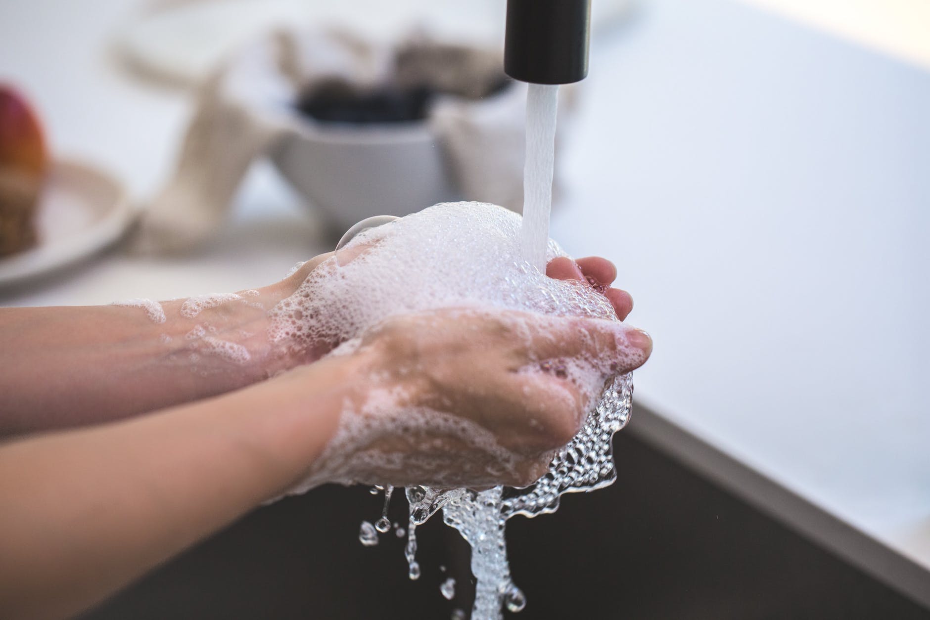 Jeune femme qui se lave les mains avec l'eau du robinet